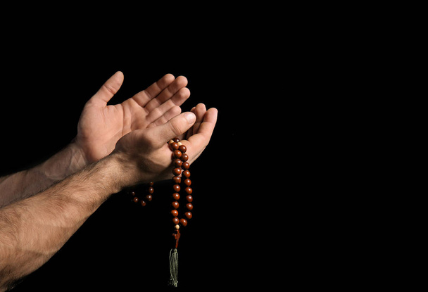 Male hands with rosary beads on black background - Foto, imagen