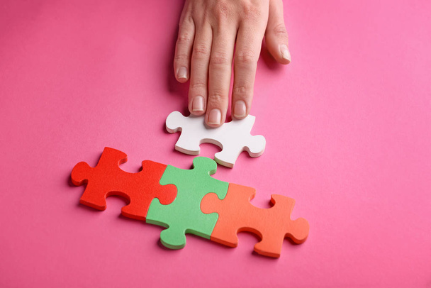 weibliche Hand mit Puzzleteilen auf farbigem Hintergrund - Foto, Bild