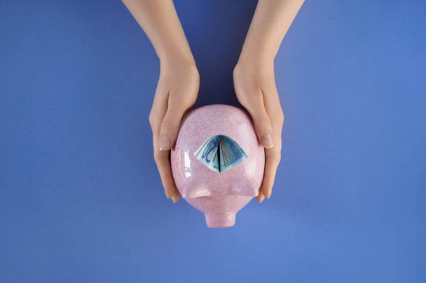 Woman holding piggy bank on color background - Photo, Image