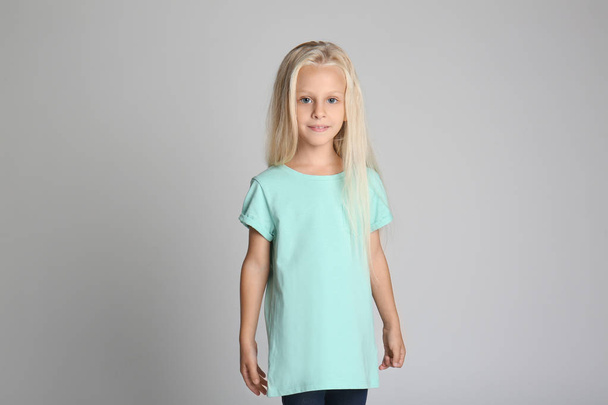 Söpö pieni tyttö t-paidassa harmaalla taustalla
 - Valokuva, kuva