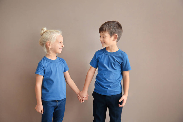 Junge und Mädchen in T-Shirts halten Händchen auf farbigem Hintergrund - Foto, Bild