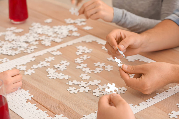 Gruppe von Menschen montiert Puzzle auf Holztisch - Foto, Bild