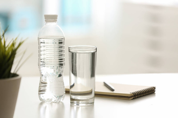 Пляшка і склянка з прісною водою на столі
 - Фото, зображення