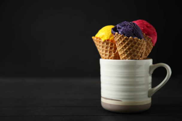 Waffle cones with delicious ice color cream in cup on wooden table - Photo, Image