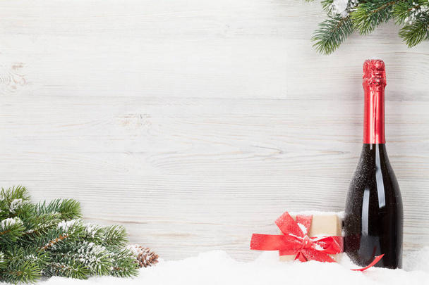 Рождественская подарочная коробка, бутылка шампанского и ветка елки. Вид с пространством для приветствий
 - Фото, изображение