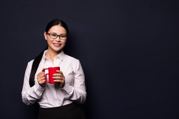 Businesswoman enjoying coffee break holding red cup - Фото, зображення