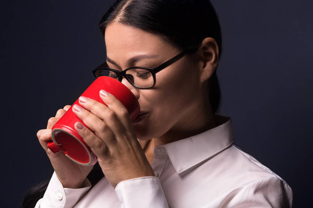 Businesswoman enjoying coffee break holding red cup - Photo, image