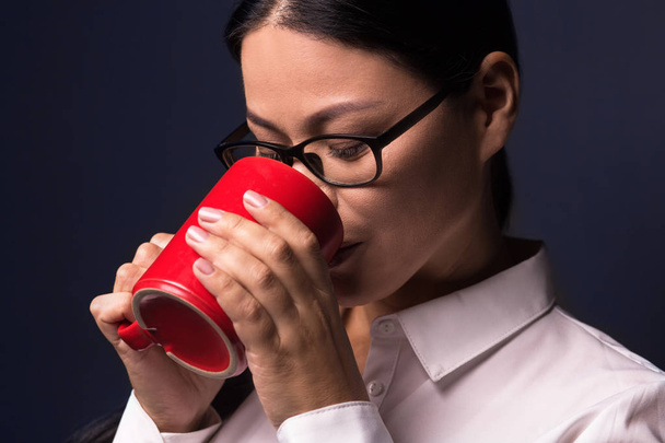 Businesswoman enjoying coffee break holding red cup - Фото, зображення