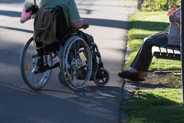 lors d'une soirée en juin en Allemagne du sud dans le parc central d'une ville historique, vous voyez couple avec fauteuil roulant se déplaçant à travers le parc ombre donnant
 - Photo, image
