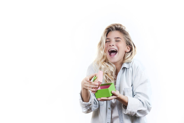 a very beautiful young emotional girl rejoices at the received gift and screams with happiness on a white isolated background - Фото, зображення