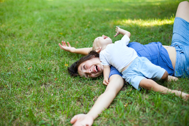 Mother and son having fun on the grass in park - Fotoğraf, Görsel