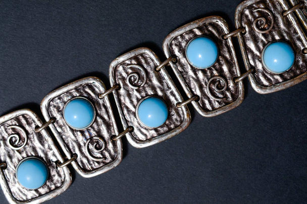серебряный браслет с голубыми камнями на черном фоне
 - Фото, изображение