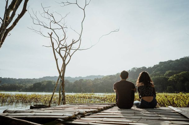couple sitting on a floating wooden board on a lake - Foto, Imagen
