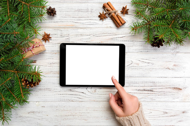 Χριστουγεννιάτικες online αγορές. Γυναικείο χέρι αφής οθόνης tablet, θέα πάνω στο ξύλινο bakground, αντίγραφο χώρου. Χειμερινές διακοπές πωλήσεων φόντο. - Φωτογραφία, εικόνα