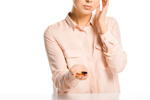 imagen recortada de la mujer sosteniendo píldoras y tocando la cabeza aislada en blanco
 - Foto, imagen