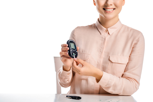 cropped image of smiling woman putting strip into glucometer isolated on white, diabetes concept - Foto, afbeelding