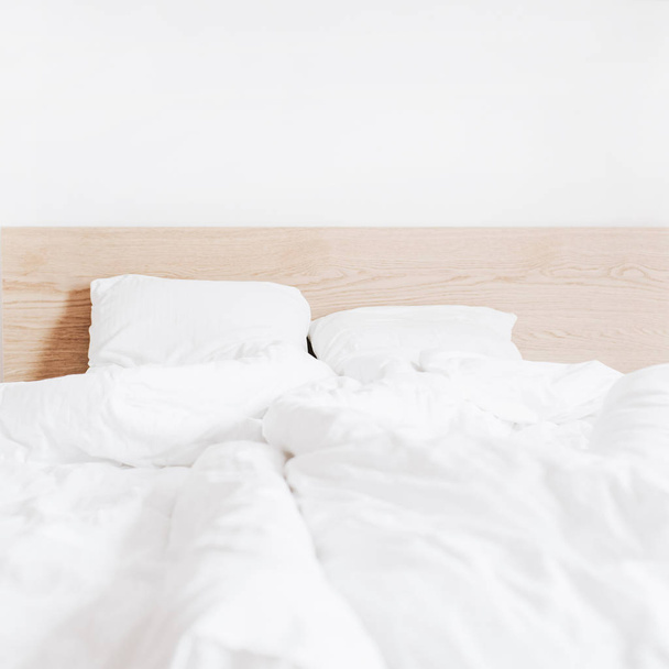 Ліжко з чистою білою постільною білизною та білою стіною. Квартири в оренду концепція. Інтер'єр
. - Фото, зображення