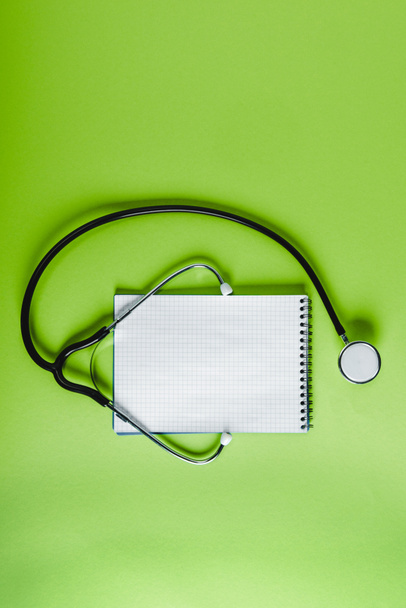 top view of stethoscope and empty notebook on green surface - Fotoğraf, Görsel