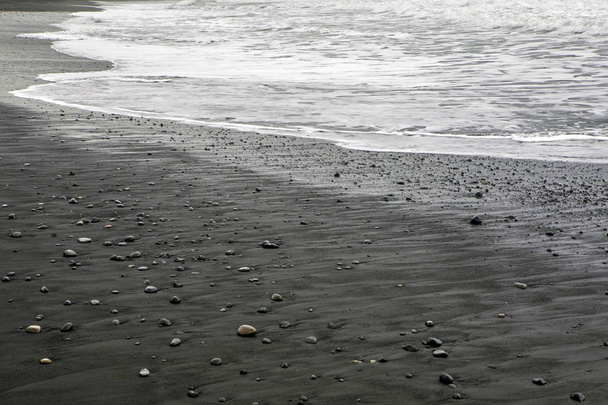 A view of the black sand on Reynisfjara Beach, near the fishing village of Vik on the south coast of Iceland. - Zdjęcie, obraz