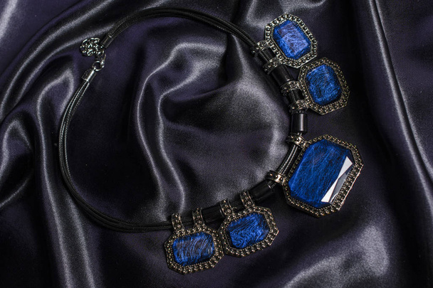 Necklace with blue stones on silk background - Foto, imagen