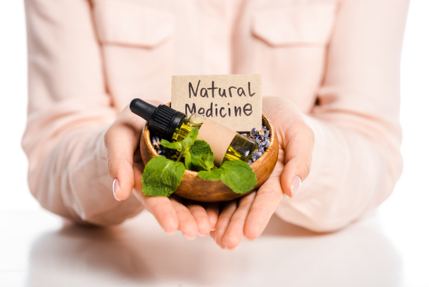 cropped image of woman holding bowl with essential oil and natural medicine sign isolated on white - Photo, Image