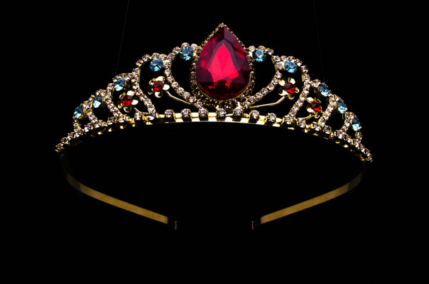 corona de oro con piedra de rubí rojo aislado en negro
 - Foto, imagen