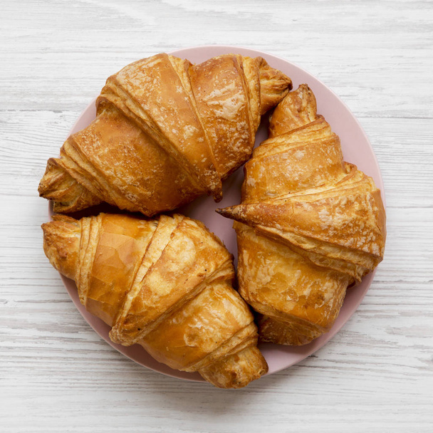 Fresh croissants with golden crust on white wooden table, overhead view. From above, flat lay. - Photo, Image