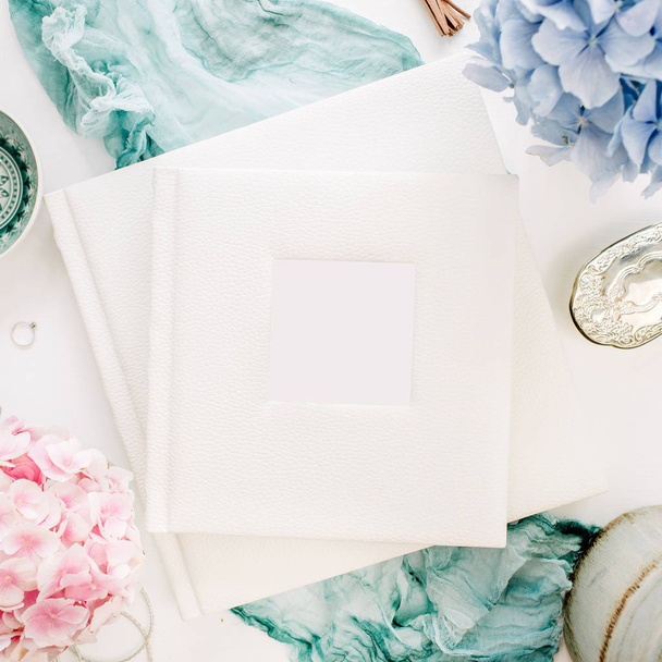 Family wedding photo album, pastel colorful hydrangea flower bouquet, turquoise blanket, decoration on white background. Flat lay, top view festive mockup. - Photo, Image