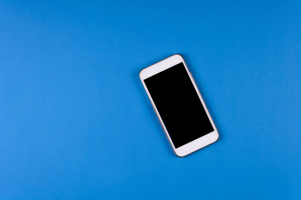 Mock-up smartphone on blue background. Flat lay. Copy space. Top view - Zdjęcie, obraz