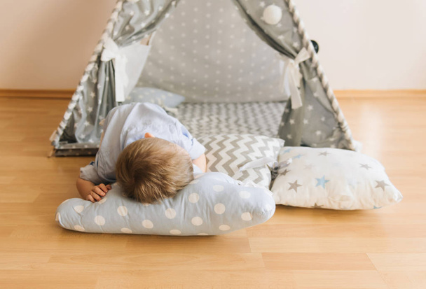 Cute one year old baby sleeping in a tent, wigwam. Shadow depth of field, natural light. The interior of the children's room is grey, blue and white - Fotoğraf, Görsel