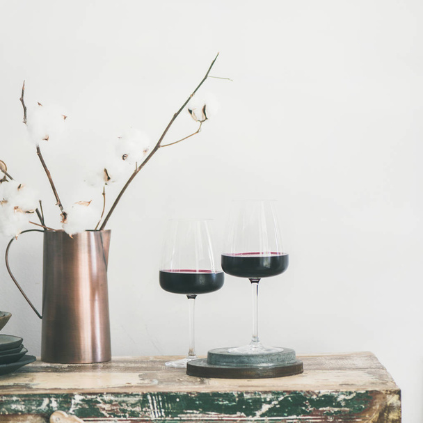 Two glasses of red wine over rustic kitchen countertop, white background behind, copy space, square crop. Wine shop, winery, bojole nouveau holiday concept - Foto, Imagem
