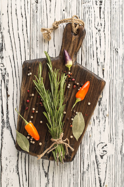 Cutting Board, rosemary and spices. background rosemary, chili pepper on a wooden table.  Herb and spice ingredients on  wooden white background - Photo, Image