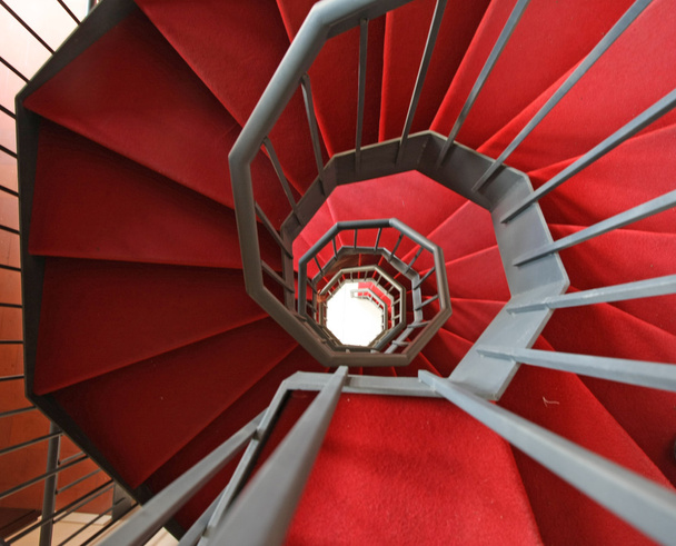 Залізні спіральні сходи з елегантним червоним килимом і спіральними
 - Фото, зображення