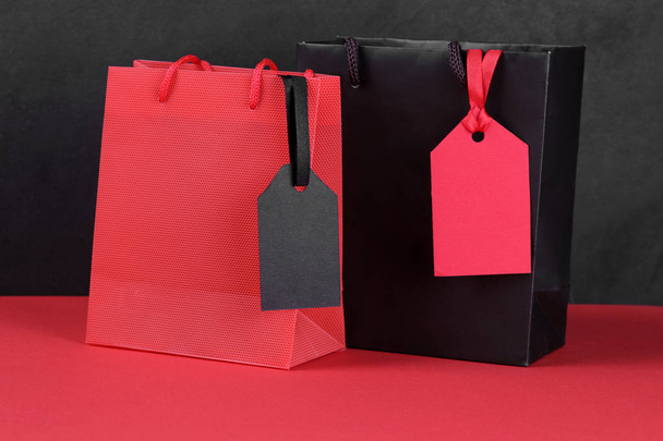 Schwarzer Freitag. Preisschilder zum Verkauf in einer Verpackung auf rotem Tisch und schwarzem Hintergrund - Foto, Bild