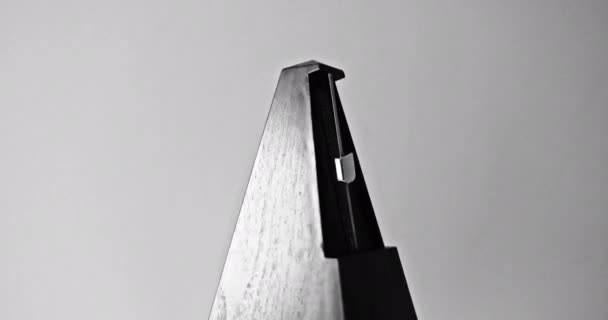 Close-up shot van vintage metronoom met slinger slaat traag ritme op de grijze achtergrond - Video
