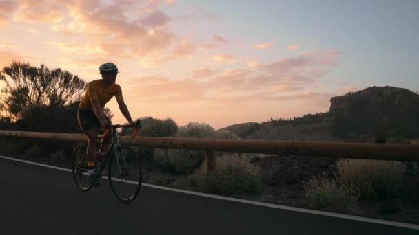 Sarı tişört adam bisikletçi karayolu üzerinde günbatımında bir dağ bisikleti rides - Video, Çekim