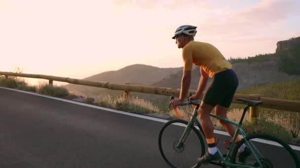 Polkupyörän urheilija kulkee vuoristoradalla olevasta kivestä katsoen kaunista näkymää saarelle. Terveellisen elämäntavan käsite
 - Materiaali, video