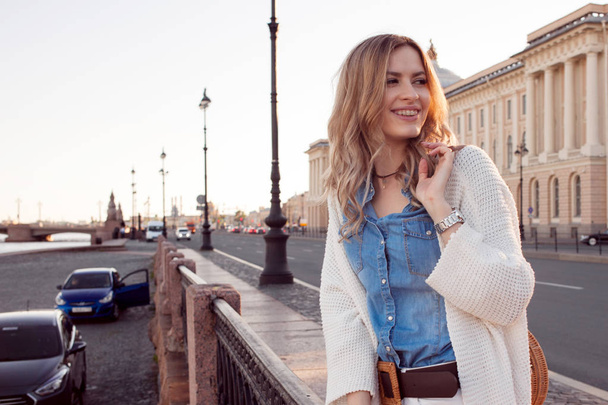 Portrait of smiling woman in a white cardigan. Laughing girl on the background of street - Foto, Bild