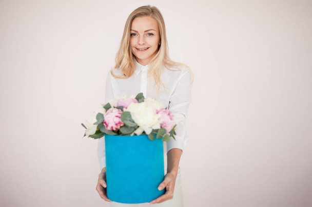 Woman with flowers in a hat box. Bouquet of peonies. Girl in business style, receives flowers or gives, Blue box. - Fotografie, Obrázek