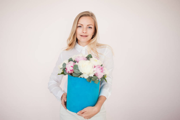 Woman with flowers in a hat box. Bouquet of peonies. Girl in business style, receives flowers or gives, Blue box. - Valokuva, kuva
