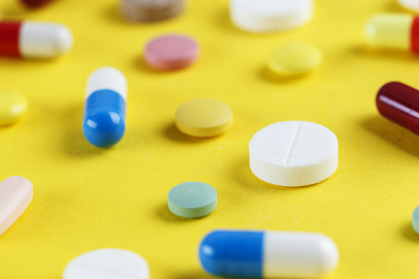 different pills and capsules scattered on a yellow background, space for tex - Photo, Image