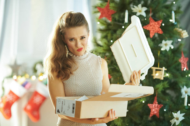unhappy young woman with broken dish from parcel near Christmas tree - Fotografie, Obrázek