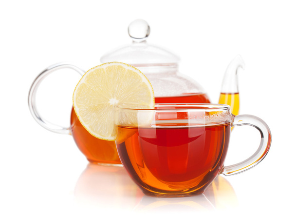 Copa de vidrio con rodaja de limón y tetera de té negro
 - Foto, imagen