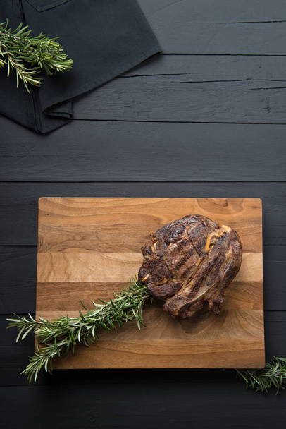 roasted meat with greens on a cutting board on a black wooden background - Фото, зображення