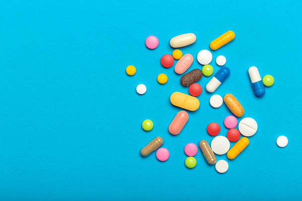 close up view of Pills scattered over blue background - Фото, изображение