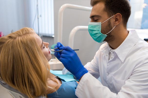 handsome young dentist examining teeth of female client - Foto, Imagem