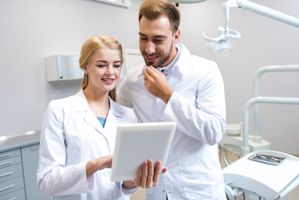 young male and female dentists working with tablet together - Fotoğraf, Görsel