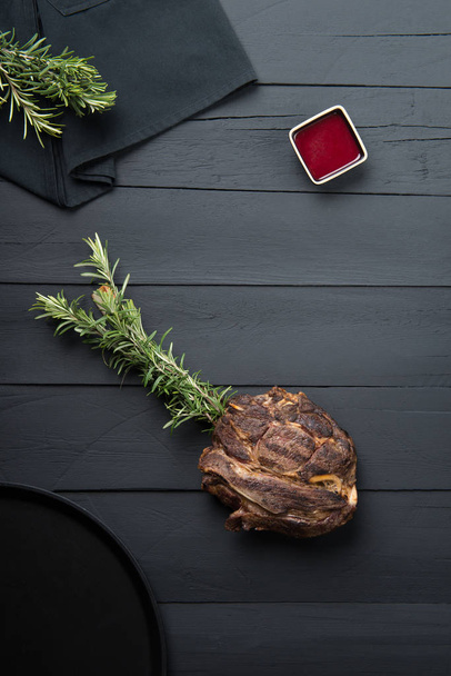 carne frita con verduras, salsa y salsa sobre un fondo de madera negro
 - Foto, imagen