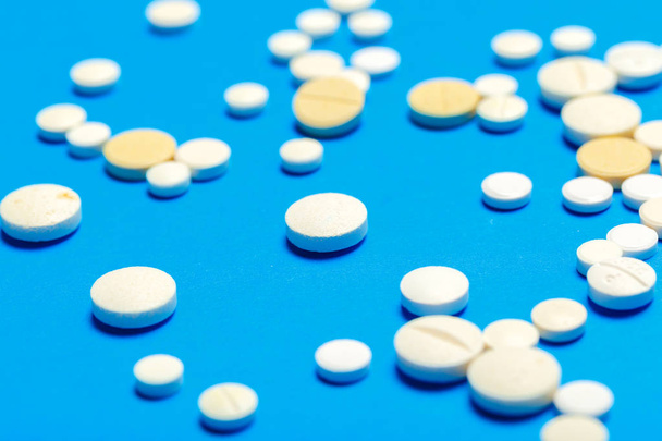 Pills are scattered over a blue background - Foto, afbeelding