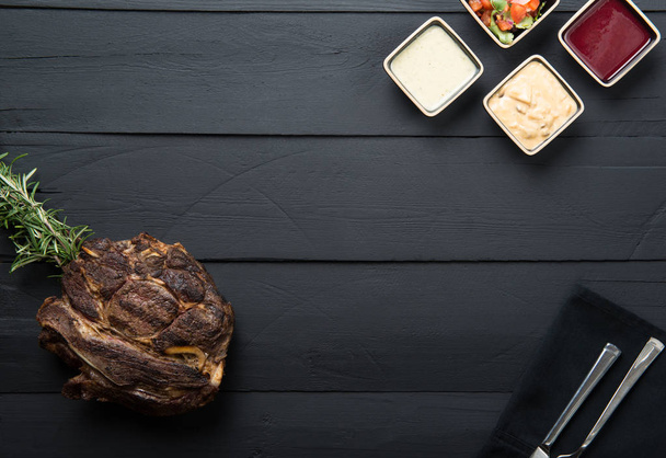 gebakken vlees met Groenen, saus en jus op een zwarte houten achtergrond - Foto, afbeelding